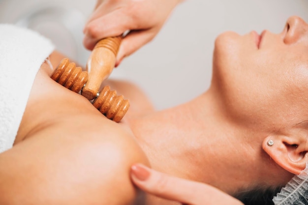 Maderotherapy Anti-Aging-Massagebehandlung des Dekolletés und des Halses der Frau mit Holzrolle