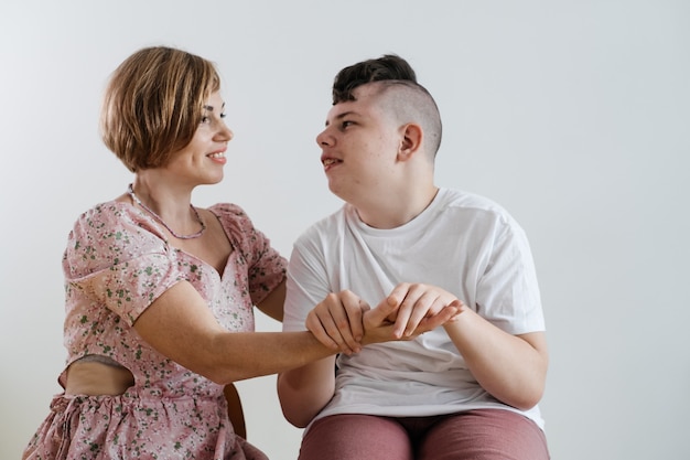 Madre abrazando a un niño discapacitado en silla de ruedas con parálisis cerebral