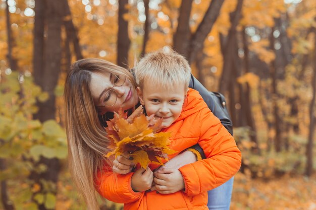 Madre abrazando a su hijo durante la caminata en el parque otoño temporada de otoño y concepto monoparental