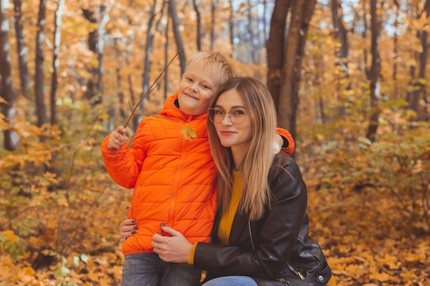 Madre abrazando a su hijo durante la caminata en el parque otoño temporada de otoño y concepto monoparental