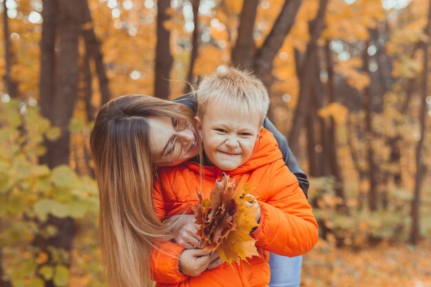 Madre abrazando a su hijo durante la caminata en el parque otoño temporada de otoño y concepto monoparental
