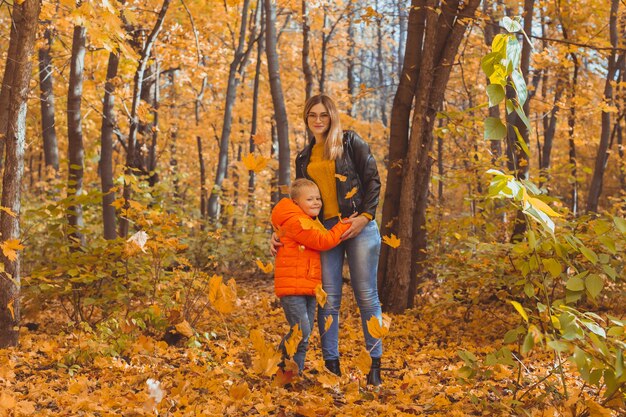 Madre abrazando a su hijo durante la caminata en el parque otoño temporada de otoño y concepto monoparental