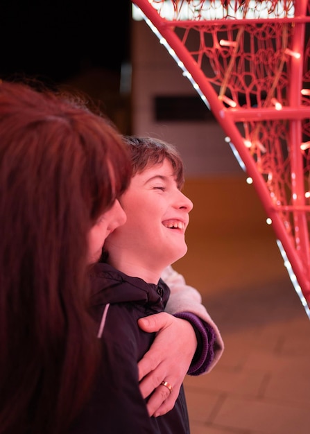 Madre abrazando a su hijo bajo luces rojas en las noches El niño está feliz y riendo