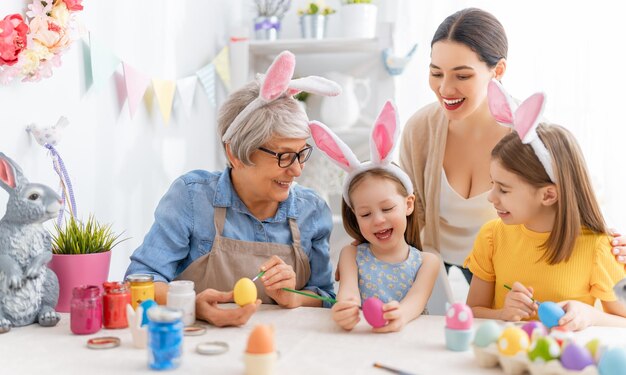 Madre abuela e hijas están pintando huevos La familia feliz se está preparando para Pascua