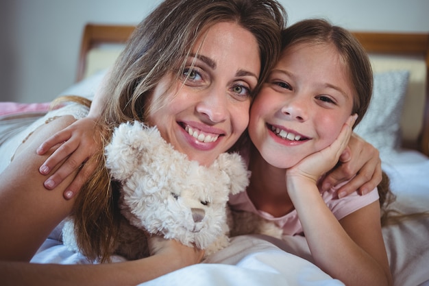 Madre acostada con hija en la cama