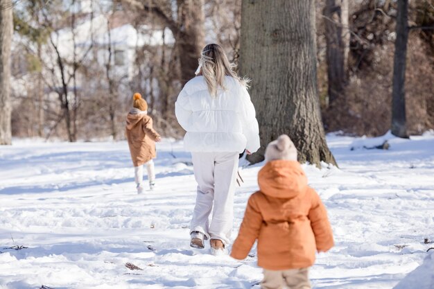 Una madre activa y feliz camina por un sendero en el bosque de invierno junto con sus hijos pequeños Fiestas familiares de invierno Feliz maternidad