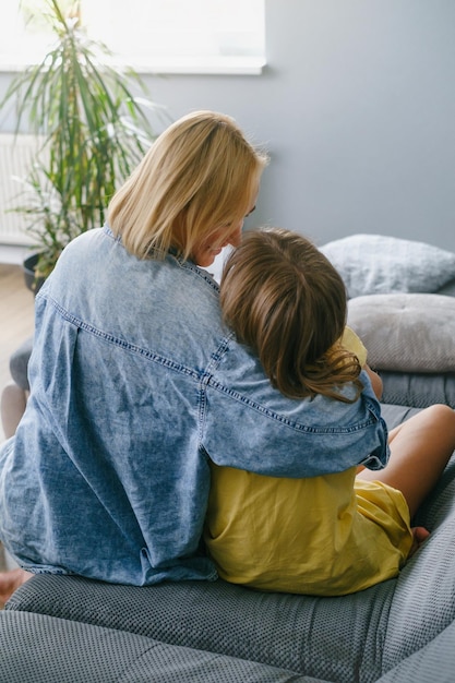 Foto madre con una adolescente abrazada en el sofá