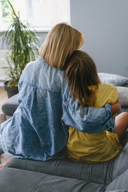 Foto madre con una adolescente abrazada en el sofá