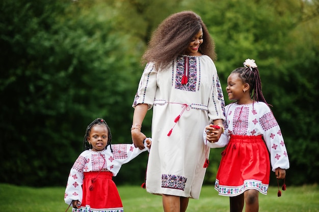 Madre africana con hijas vestidas con ropa tradicional en el parque.
