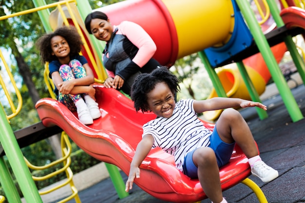 Madre africana con sus dos hijos divirtiéndose en un parque
