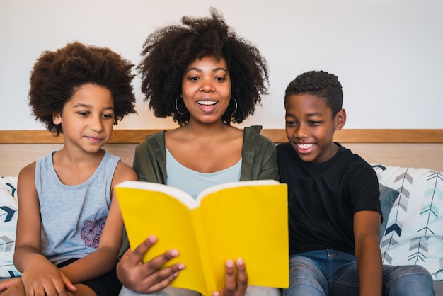 Madre afro leyendo un libro a sus hijos.