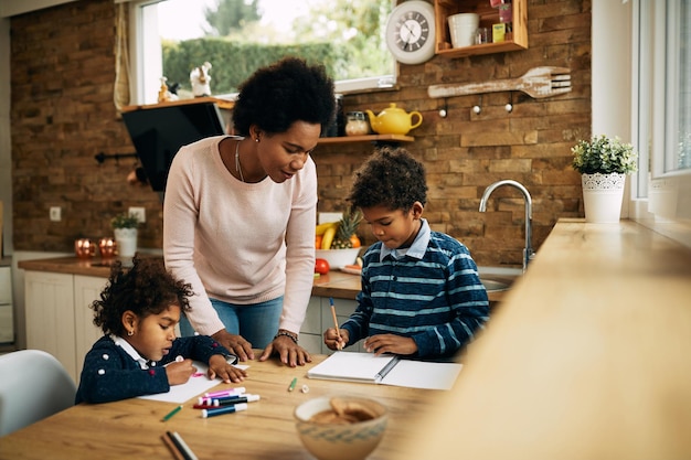 Madre afroamericana ayudando a sus hijos a aprender en casa