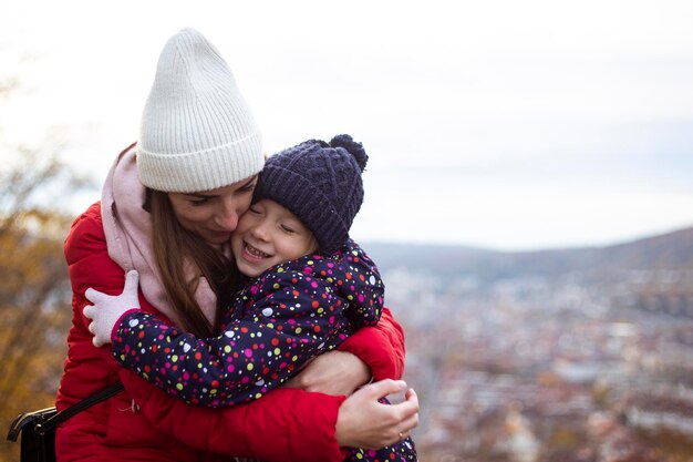 Madre alegre abrazando a su pequeña hija con el telón de fondo de una vista panorámica