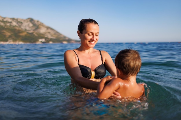 Madre alegre juega con su hijo en el mar