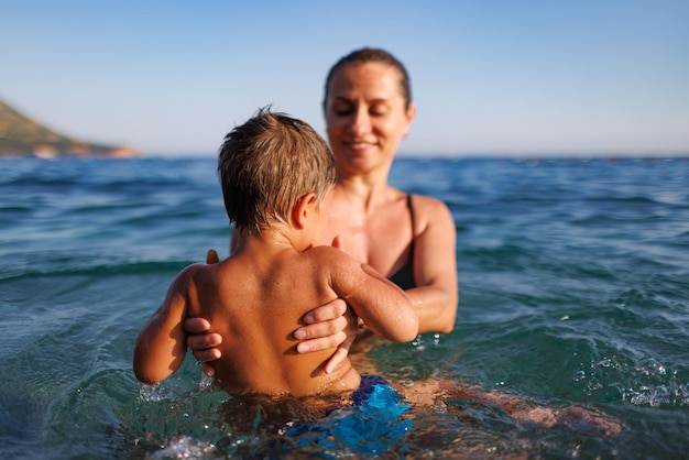 Madre alegre juega con su hijo en el mar