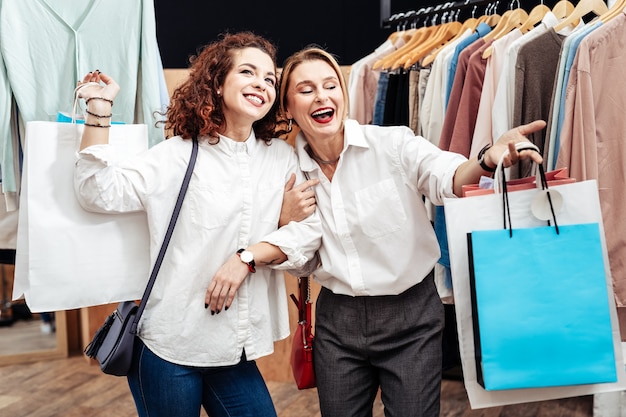 Madre alegre. Madre madura de pelo rubio que se siente alegre pasar tiempo de compras con su chica