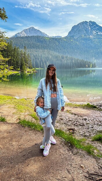 Madre alegre con su hija en el hermoso lago de Montenegro