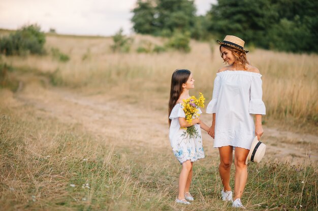 Madre alegre y su pequeña hija divirtiéndose juntos en la superficie de verano