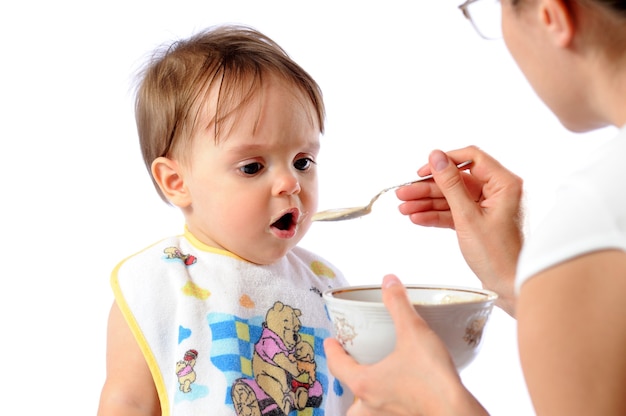 La madre alimenta a la niña con una cuchara