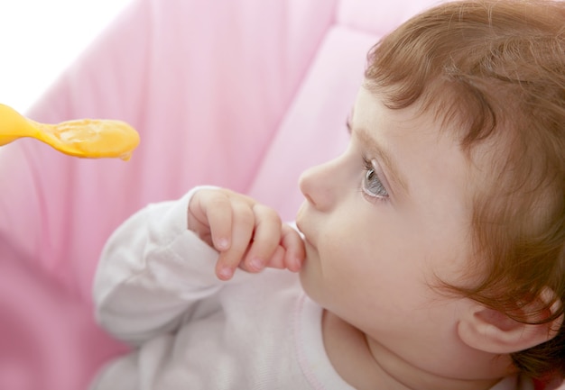 Madre alimentando al bebé cuchara amarilla