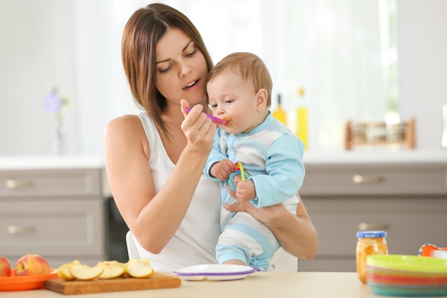 Foto madre alimentando al bebé con una cuchara en el interior