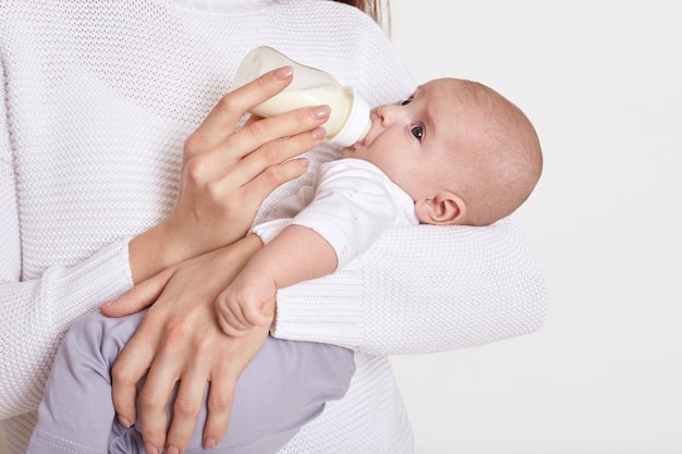 Madre alimentando de biberón a su bebé aislado sobre blanco