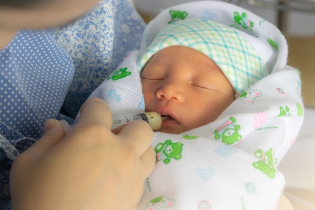 Foto madre alimentando leche de bebé recién nacido con jeringa