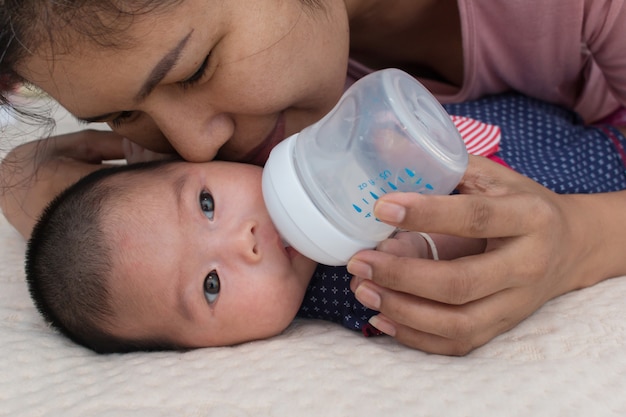 Madre alimentando leche y besando a su bebé.