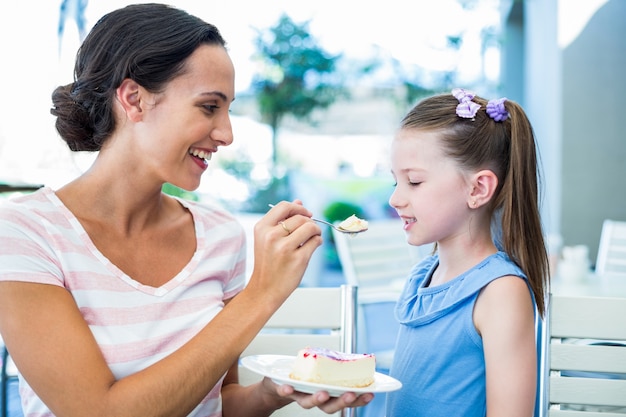 Madre alimentando a su hija con pastel