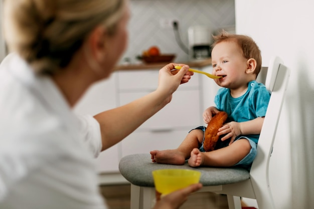 Madre alimentando a su hijo en casa