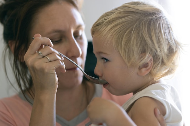 Foto madre alimentando a su pequeño hijo con la cuchara