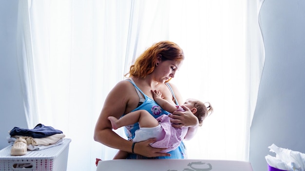 Foto madre amamantando al bebé cerca de la ventana