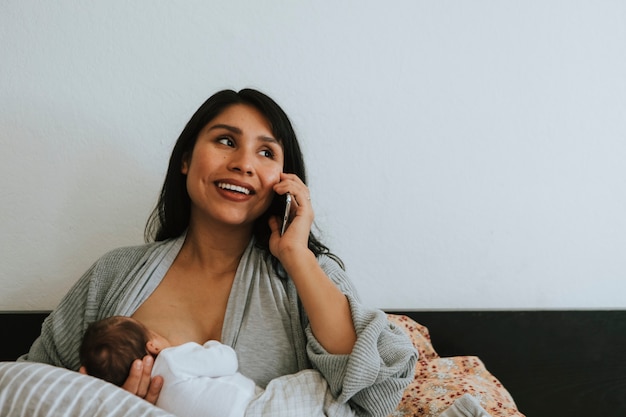 Madre amamantando mientras habla por teléfono.