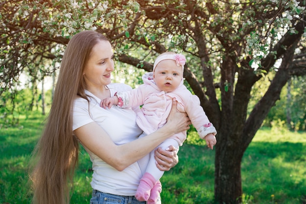 Madre con amor y ternura mira al niño. Mamá sostenga a la pequeña hija en las manos. Concepto de maternidad de la paternidad.