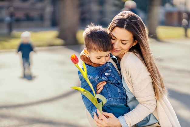 Una madre amorosa abrazando a su hijo y agradeciéndole una flor en el día de la madre