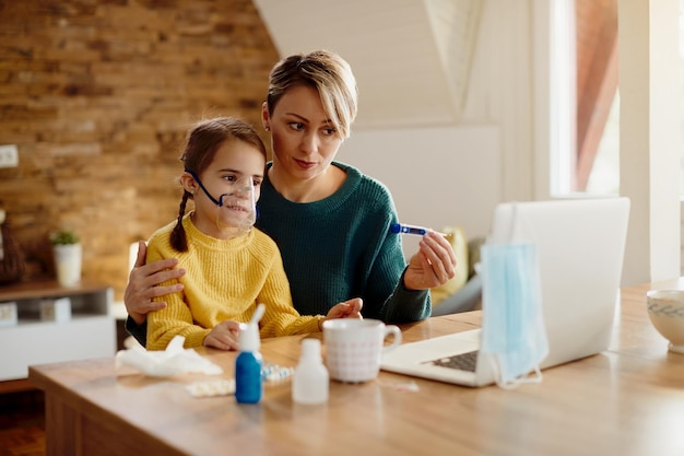 Madre angustiada y su pequeña hija haciendo videollamadas con un médico desde casa