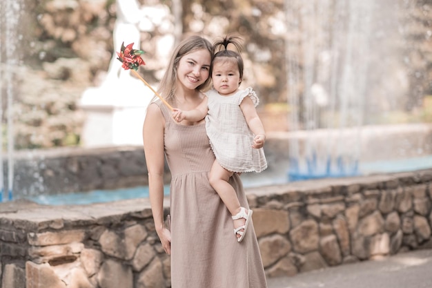 Foto una madre de apariencia eslava abraza a su hija asiática mientras camina