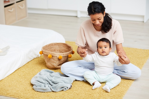 Madre aprendiendo a su bebé a sentarse