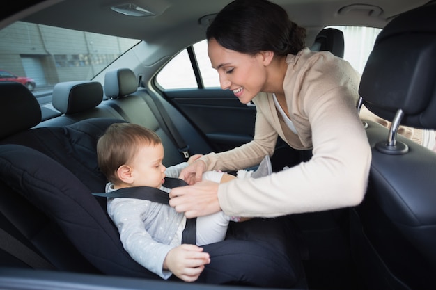 Madre asegurando a su bebé en la silla de auto