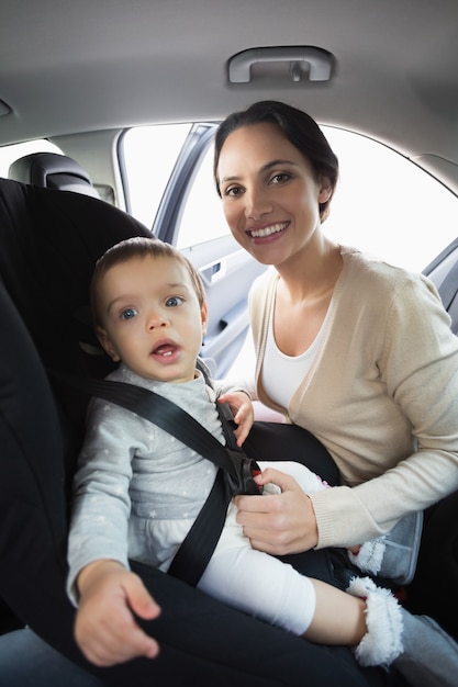 Madre asegurando a su bebé en la silla de auto