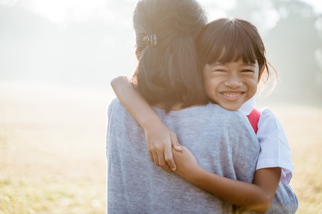 Madre asiática abraza y abraza a su hija yendo a la escuela