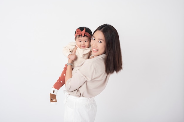 Madre asiática y adorable niña son felices en la pared blanca