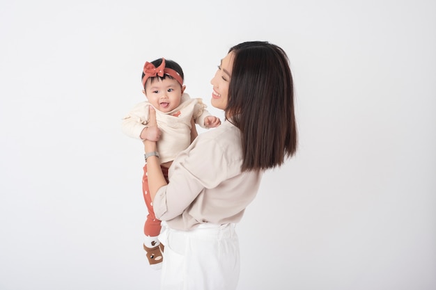 Madre asiática y adorable niña son felices en la pared blanca