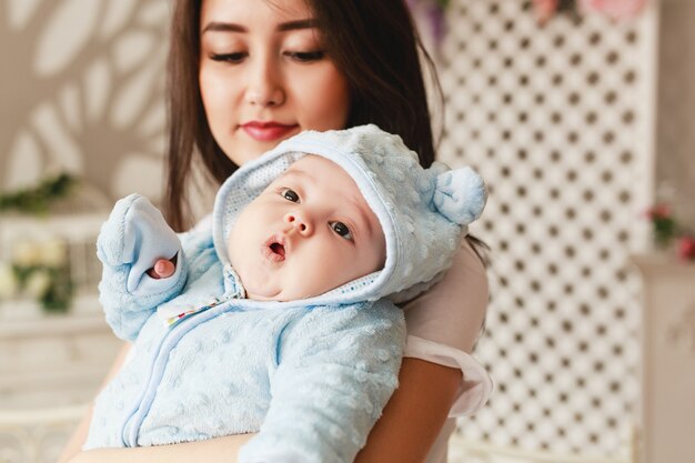 Madre asiática cariñosa que detiene al hijo del bebé en casa.