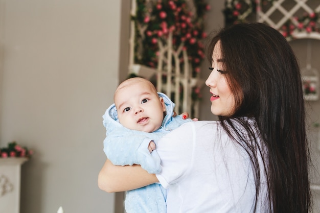 Madre asiática cariñosa que detiene al hijo del bebé en casa.