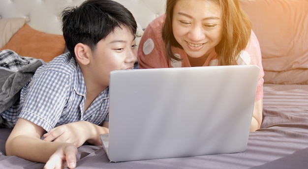 Madre asiática e hijo de la familia que miran en el ordenador portátil.