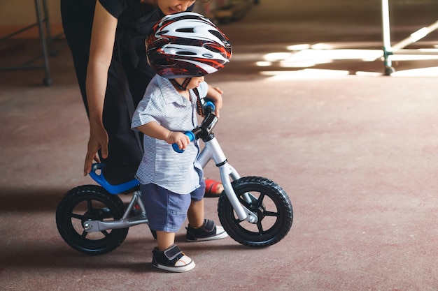 Madre asiática enseña a su hijo a jugar bicicleta de equilibrio bebé