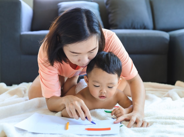 Madre asiática enseñando a su bebé dibujar