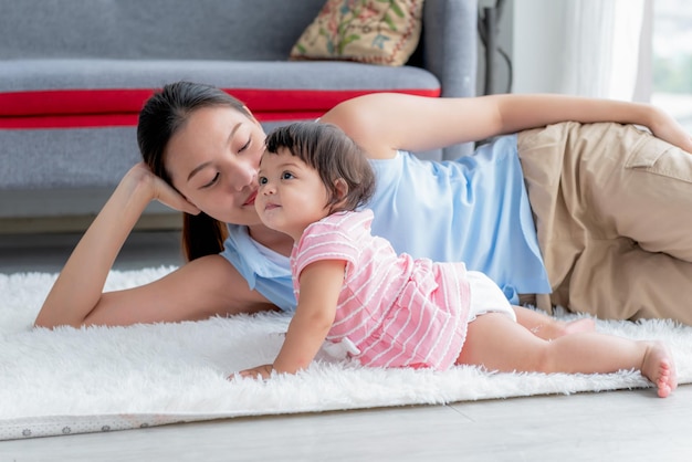 Madre asiática y hija de 7 meses sentados en el suelo están relajados y felices juntos a la relación en la familia y el concepto de bebé lindo