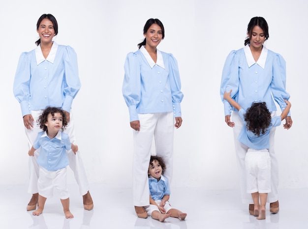 La madre asiática y la hija caucásica se ponen de pie y visten juntas el mismo pantalón azul. La niña toma la mano de mamá y sonríe con amor. Fondo blanco aislado